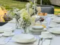 Elegancko nakryty stół na 23 rocznicę ślubu. Biała zastawa, świeże kwiaty i świece tworzą romantyczną atmosferę.