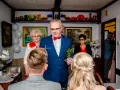Uroczysty błogosławieństwo przed ślubem cywilnym. Mężczyzna w garniturze trzyma krzyżyk i gałązkę.