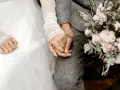 Dłonie młodej pary splecione, ozdobione pierścionkiem. Bukiet róż i zieleni. Idealny moment na wierszyk na błogosławieństwo młodej pary od dziecka.