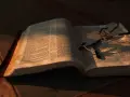 Otwarta Biblia z okularami, oświetlona ciepłym światłem. Co znaczy vel przed nazwiskiem? To skrót od "vel" (łac. "albo"), używany w dokumentach, by wskazać alternatywne nazwisko.