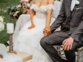 Para szybko wziąć ślub kościelny, para młoda trzyma się za ręce. Panna młoda w sukni z koronki, pan młody w garniturze.