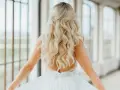 Piękna panna młoda z blond lokami i złotą ozdobą we włosach. Delikatne fale na włosach dodają jej uroku w tym wyjątkowym dniu wesela.
