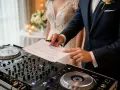 Pan młody podpisuje umowę DJ-owi, który przygotowuje się do wesela.