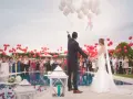 Para młoda wypuszcza balony podczas wesela w piątek. Goście trzymają czerwone balony, a para młoda białe.