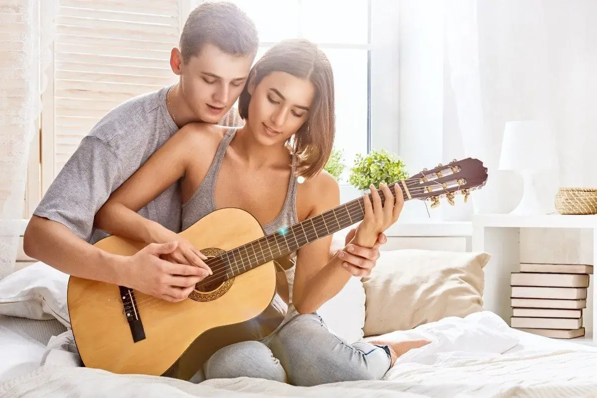 Para grająca na gitarze, tworząc romantyczną atmosferę. Idealna do słuchania najpiękniejszych piosenek o miłości po angielsku.