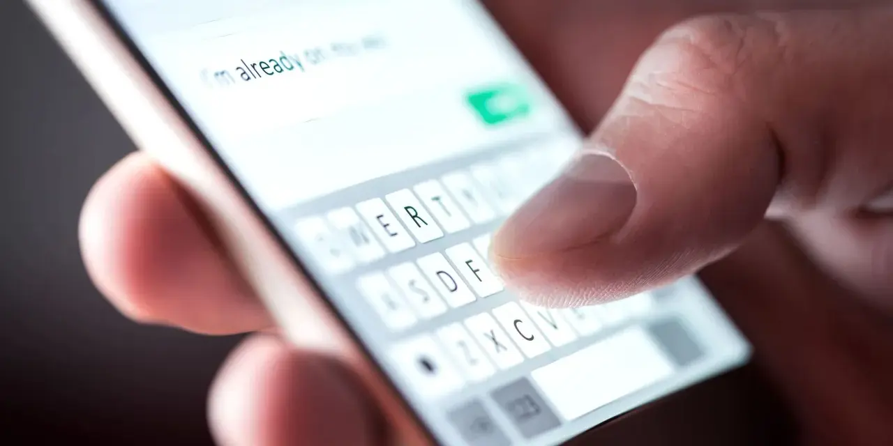 Palec pisze na smartfonie "Już jestem", potwierdzenie przybycia na wesele sms.