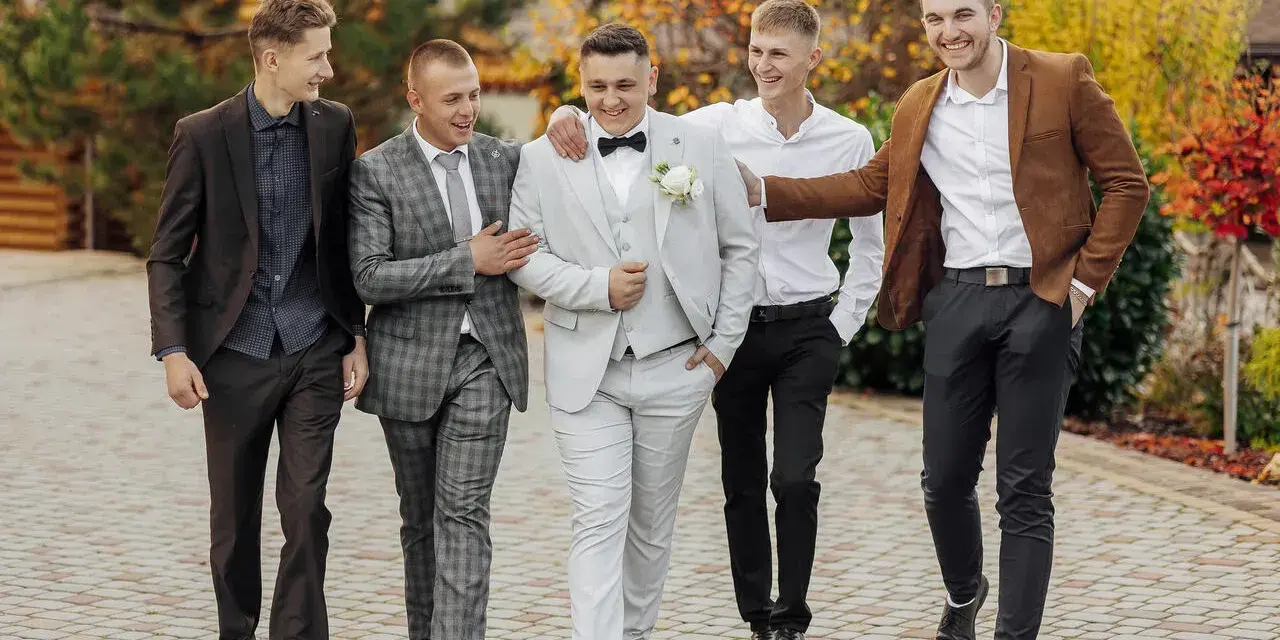 Pięciu panów w eleganckich garniturach, idealny dress code na wesele.