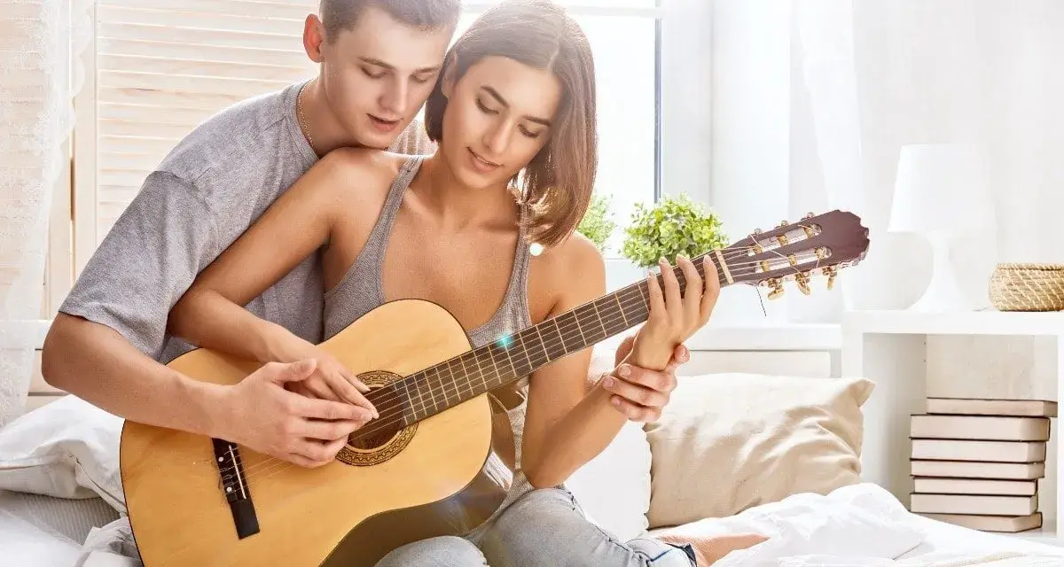 Para grająca na gitarze, tworząc romantyczną atmosferę. Idealna do słuchania najpiękniejszych piosenek o miłości po angielsku.