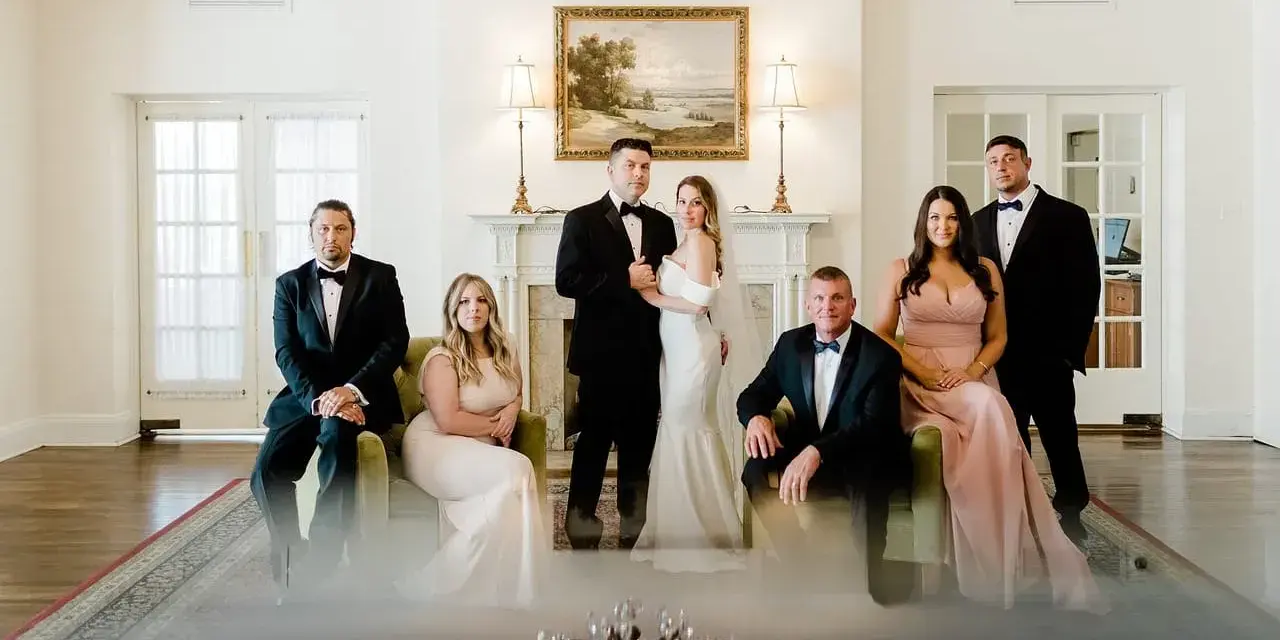 Rodzina w eleganckich strojach pozuje do zdjęcia. Panna młoda w białej sukni i pan młody w smokingu, obok nich świadkowie. Zastanawiasz się, jakie dokumenty do ślubu kościelnego są potrzebne?