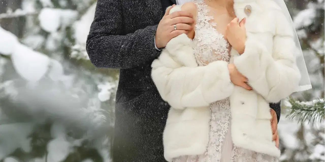 Para młoda w zimowej scenerii. Delikatny śnieg otula ich w dniu ślubu w grudniu.