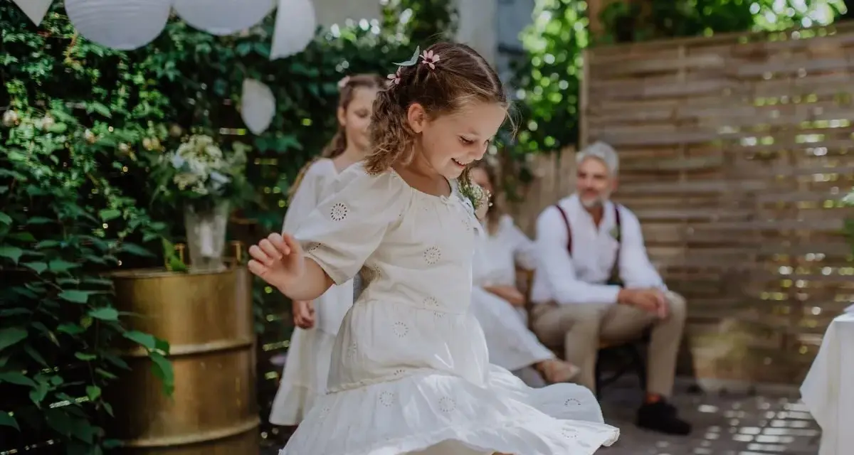 Urocza fryzura dla dziewczynki na wesele, z warkoczykami i kwiatkami, idealna do tańca.