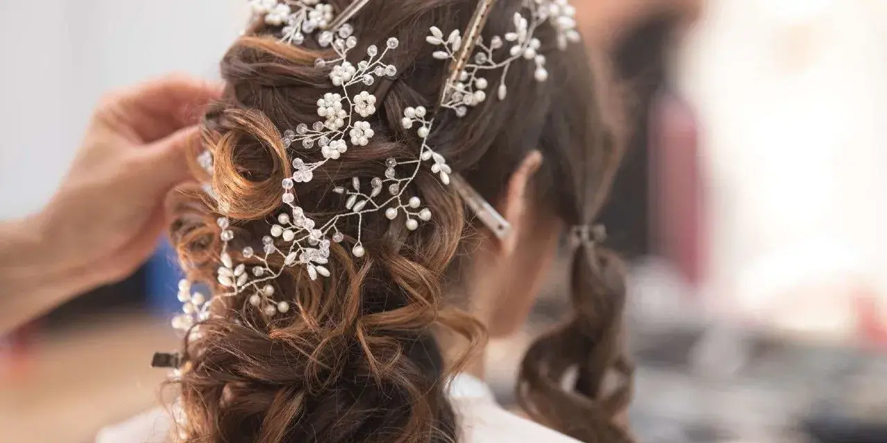 Eleganckie fryzury ślubne z perłami i kryształkami, tworzące romantyczny wianek na brązowych włosach.