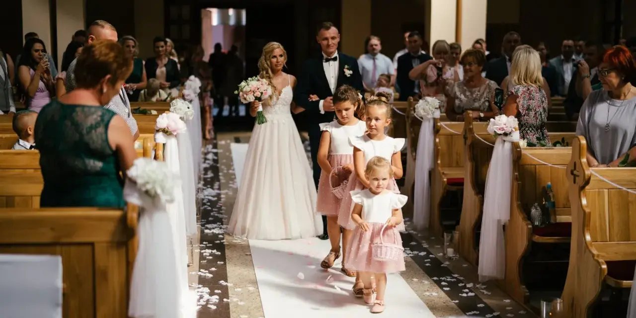 Panna młoda z bukietem idzie do ołtarza w kościele ślubnym, a za nią podążają dziewczynki sypiące kwiaty.