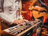 Muzyk gra na keyboardzie, tworząc tło dla najpiękniejszych piosenek biesiadnych. W tle widać gitarzystę.
