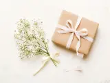 Bukiet gipsówki i prezent zawinięty w papier kraft z jasnoróżową wstążką. Czy daje się kwiaty na ślub? Tak, to piękny gest!