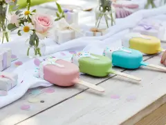 Kolorowe cake pops wesele na drewnianym stole, ozdobionym kwiatami i prezentami.