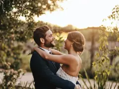 Para młoda w objęciach, uśmiechnięci do siebie. Cichy ślub kościelny bez zapowiedzi, w otoczeniu natury, w blasku słońca.