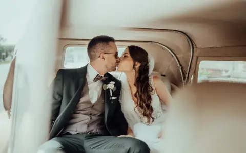 Młoda para w samochodzie, pocałunek. Dylemat podwójne nazwisko za i przeciw, czy warto?