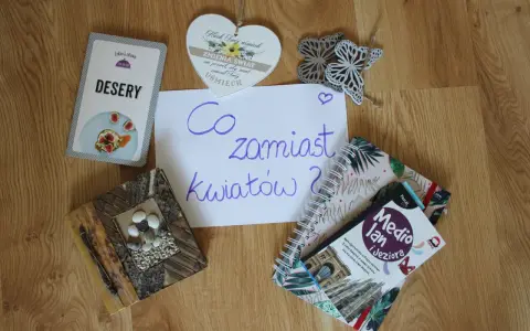 Co zamiast kwiatów na wesele? Na stole leżą karty z deserami, książki o podróżach i serce z napisem "Niech Twój uśmiech zmienia świat".