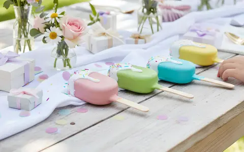 Kolorowe cake pops wesele na drewnianym stole, ozdobionym kwiatami i prezentami.