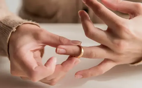 Dłoń zdejmuje złotą obrączkę z palca. Czy to znak, że zgubiona obrączka oznacza koniec związku?