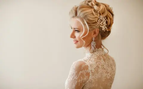 Eleganckie fryzury ślubne z welonem, zdobione perłami i kryształami, podkreślają urodę panny młodej.
