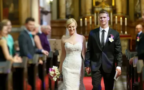 Para młoda idzie do ołtarza. Piękna suknia ślubna i elegancki garnitur świadczą o tym, że to wyjątkowy ślub po 40.