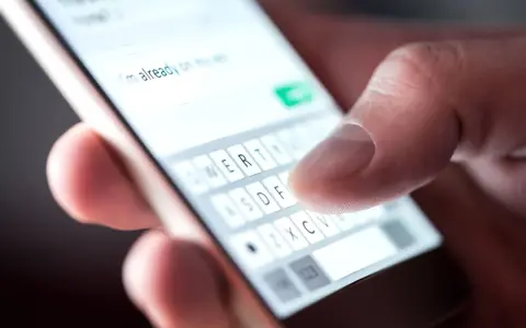 Palec pisze na smartfonie "Już jestem", potwierdzenie przybycia na wesele sms.