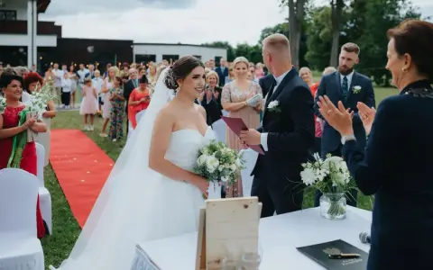 Urzędniczka udziela ślubu cywilnego parze młodej na tle gości.