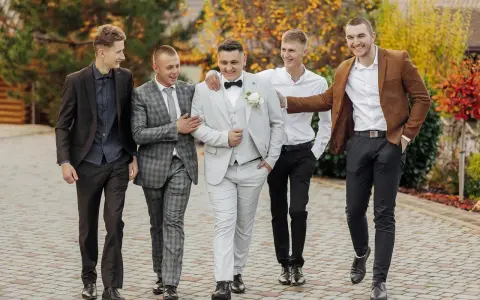 Pięciu panów w eleganckich garniturach, idealny dress code na wesele.