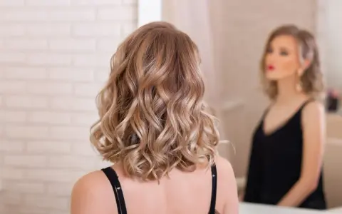 Elegancka fryzura dla świadkowej: fale na średniej długości włosach w odcieniu blondu.