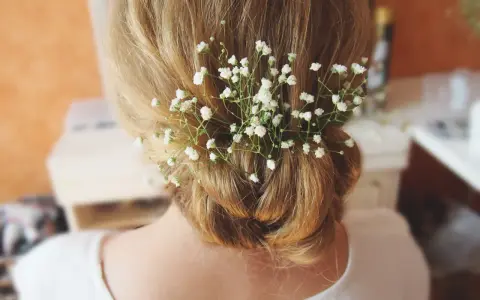 Delikatne, białe kwiaty do włosów zdobią elegancki kok.