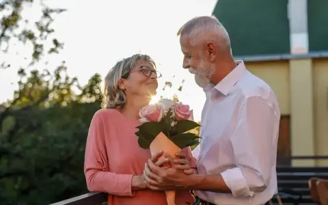 Starsza para świętuje 17 rocznicę ślubu. Mężczyzna wręcza kobiecie bukiet róż.