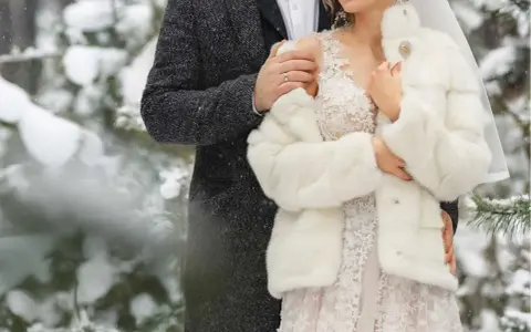 Para młoda w zimowej scenerii. Delikatny śnieg otula ich w dniu ślubu w grudniu.