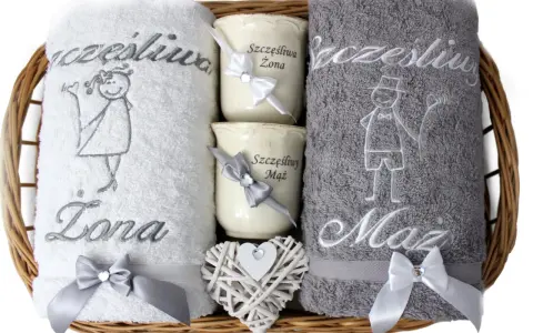 Prezent na rocznicę wełnianą: biały ręcznik "Szczęśliwa Żona" i szary "Szczęśliwy Mąż", dwa kubeczki i serce z wikliny.