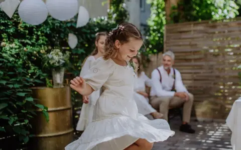 Urocza fryzura dla dziewczynki na wesele, z warkoczykami i kwiatkami, idealna do tańca.