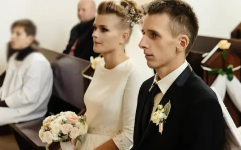 Para młoda w kościele, ona z bukietem, on w garniturze. Ceremonia ślubna, choć w żałobie, odbywa się z godnością.