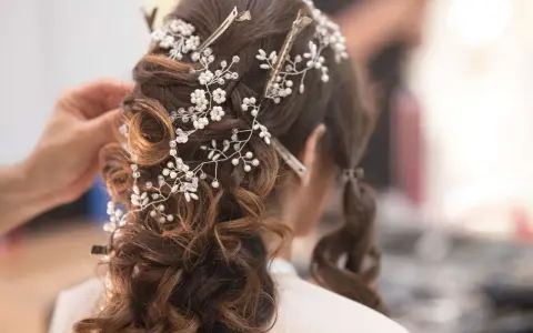 Eleganckie fryzury ślubne z perłami i kryształkami, tworzące romantyczny wianek na brązowych włosach.