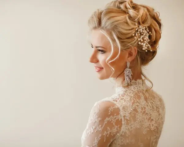Eleganckie fryzury ślubne z welonem, zdobione perłami i kryształami, podkreślają urodę panny młodej.