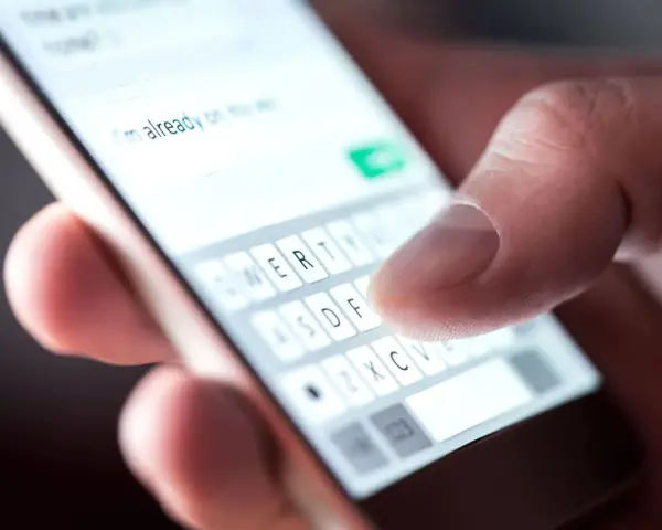 Palec pisze na smartfonie "Już jestem", potwierdzenie przybycia na wesele sms.