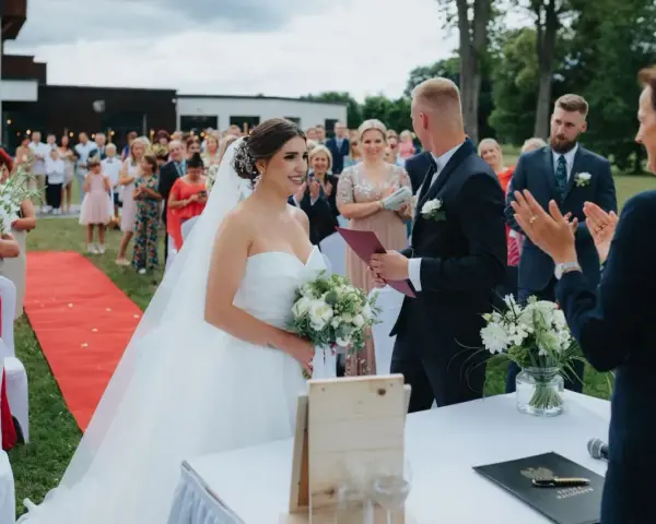 Urzędniczka udziela ślubu cywilnego parze młodej na tle gości.