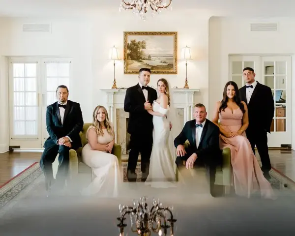 Rodzina w eleganckich strojach pozuje do zdjęcia. Panna młoda w białej sukni i pan młody w smokingu, obok nich świadkowie. Zastanawiasz się, jakie dokumenty do ślubu kościelnego są potrzebne?