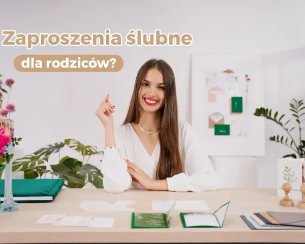 Uśmiechnięta kobieta przy biurku z zaproszeniami ślubnymi. Czy rodzicom daje się zaproszenie na ślub? Na stole leżą próbki zaproszeń i kwiaty.
