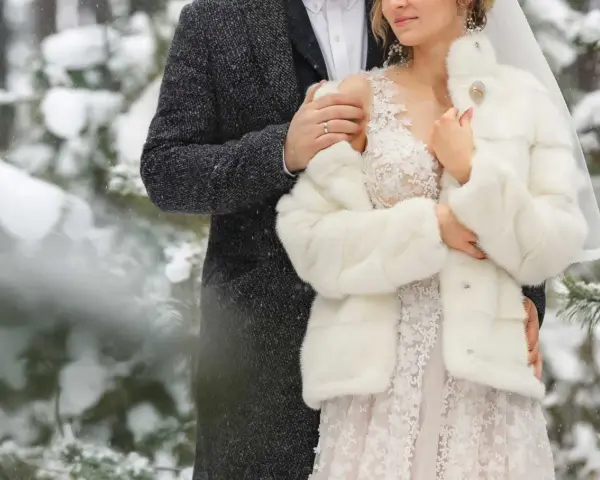 Para młoda w zimowej scenerii. Delikatny śnieg otula ich w dniu ślubu w grudniu.