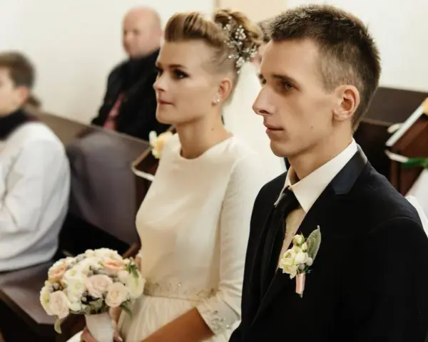 Para młoda w kościele, ona z bukietem, on w garniturze. Ceremonia ślubna, choć w żałobie, odbywa się z godnością.
