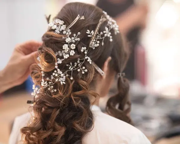 Eleganckie fryzury ślubne z perłami i kryształkami, tworzące romantyczny wianek na brązowych włosach.
