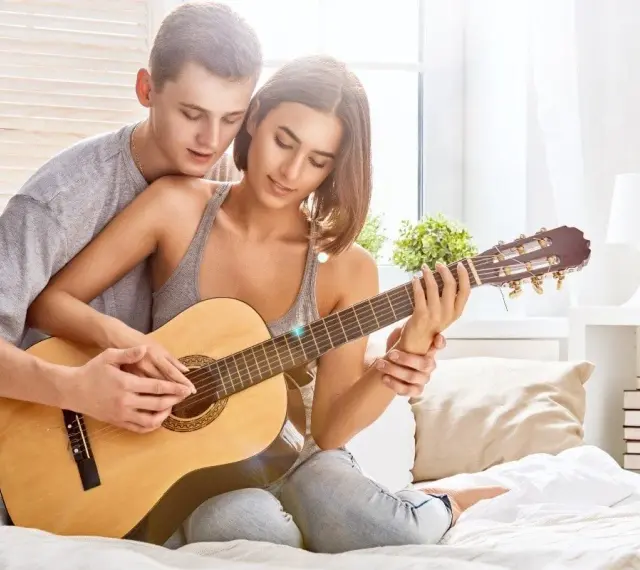 Para grająca na gitarze, tworząc romantyczną atmosferę. Idealna do słuchania najpiękniejszych piosenek o miłości po angielsku.
