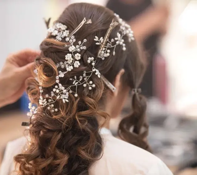 Eleganckie fryzury ślubne z perłami i kryształkami, tworzące romantyczny wianek na brązowych włosach.