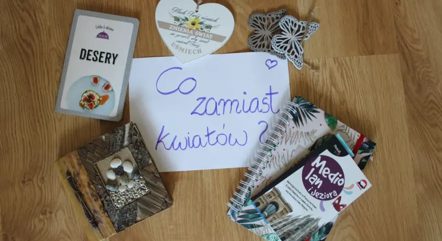 Co zamiast kwiatów na wesele? Na stole leżą karty z deserami, książki o podróżach i serce z napisem "Niech Twój uśmiech zmienia świat".
