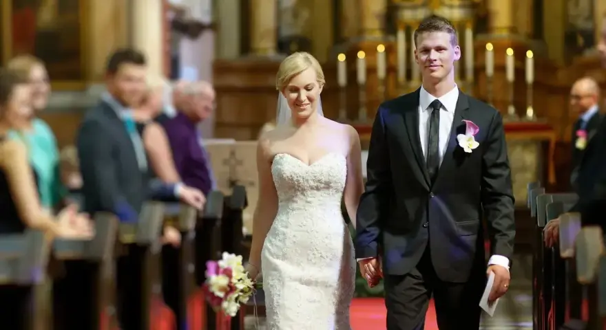 Para młoda idzie do ołtarza. Piękna suknia ślubna i elegancki garnitur świadczą o tym, że to wyjątkowy ślub po 40.